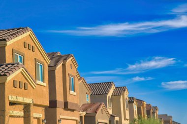 Side view of row of houses in the suburb neighborhood in Tucson, Arizona. Row of houses with painted stucco walls against the blue sky at the back.