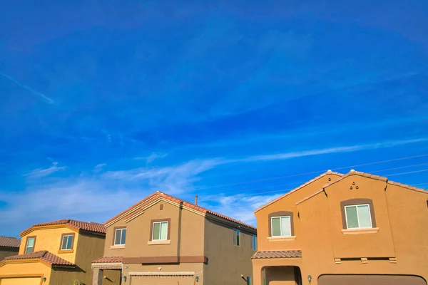 Row of houses with rustic color paint and brown trims exterior at Tucson, Arizona. Suburban houses with attached garages and there is a house in the middle with string lights at the front.