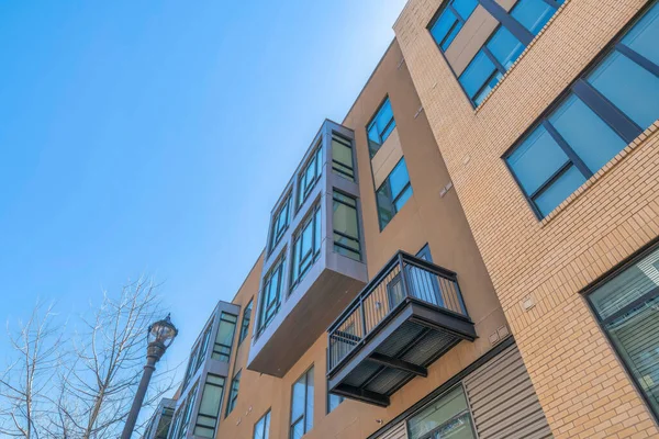 Low angle view of a low-rise residential building with reflective windows at San Antonio, Texas. Residential building with bricks, balcony, and bay windows near the lamp post on the left.