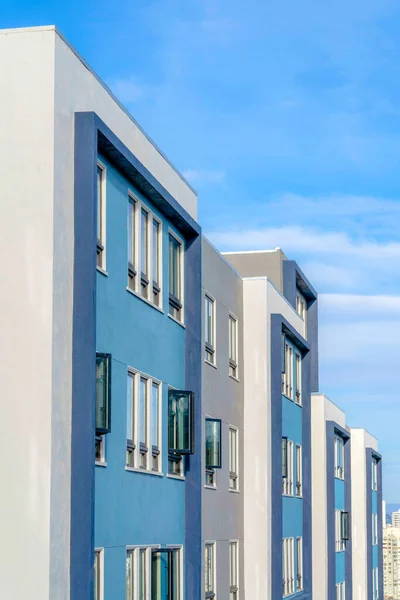 Side view of an apartment building exterior with blue and white walls in San Francisco, CA. Modern apartment with reflective casement windows.
