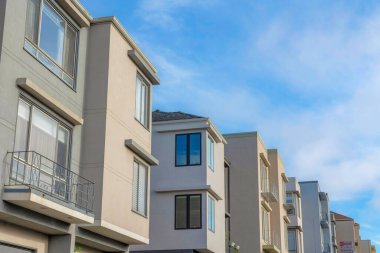 Sloped houses in San Francisco, California against the sky. Suburbs houses exterior with window railings and modern architectural structures.