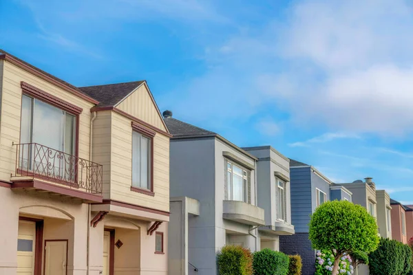 Houses with window railings in the suburbs of San Francisco, California. Front exterior of houses with a different exterior designs and shrubs at the front.