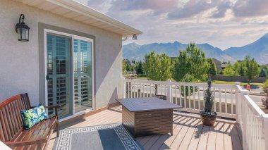 Panorama Puffy clouds at sunset Deck of a house with carpet near the bench and table. Deck of a house with a sliding glass door and a view of the trees at the neighborhood