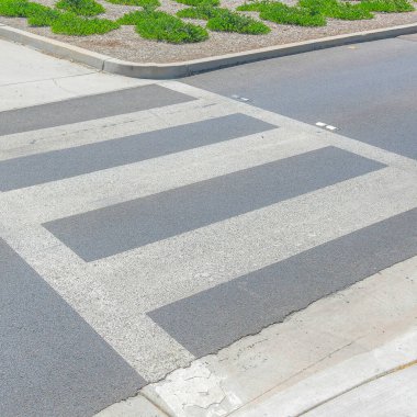Square Crosswalk with pedestrian lanes at Ladera Ranch in California. There is a crosswalk in the middle of the small island at the center of the roads with trees and sidewalks at the back.