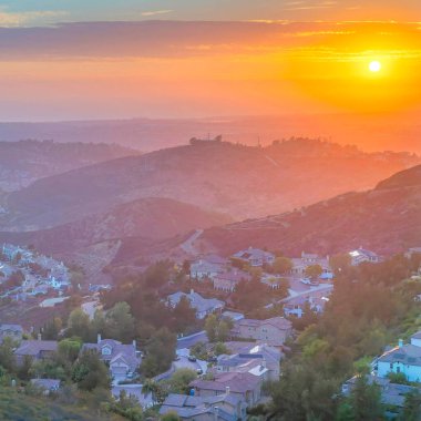 Square Dramatic sunset with clouds Aerial view of San Diego community against the sunset sky horizon. Whole view of a residential area surrounded by mountains at Southern California.