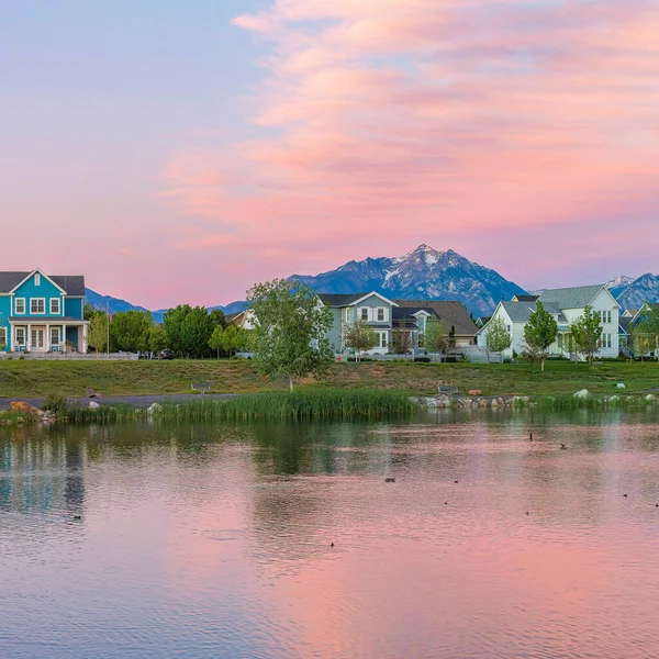 Square Reflective Oquirrh Lake waterfront at Daybreak, Utah. Panoramic view of the lake at the front of the houses and fields against the mountain range and sky