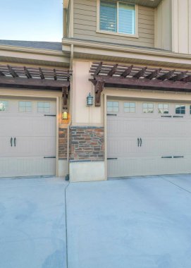 Vertical Three car parking garage with double side hinged doors. Garage exterior with pergola roofs near the front door on the right with railings and an exterior of board