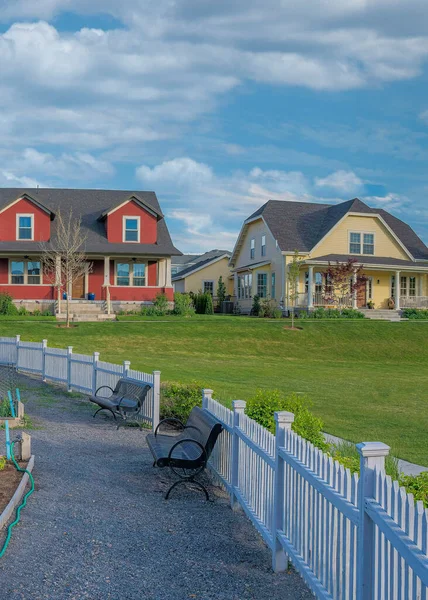 Utah, Daybreak 'te beyaz çitli dikey beyaz bulutlu halk bahçesi. Çakıl yolu ve arka planda evler ve tarlalar olan organize bir bahçe yatağında ekinler var..