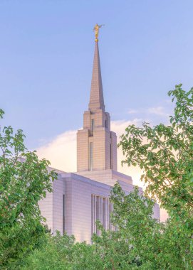 Gün batımında dikey kabarık bulutlar beton yolda her iki tarafında sütun ağaçları kiliseye doğru gidiyor. Yüksek çan kulesiyle çitli kiliseye giden yol üzerinde heykel ve mermer kiremit duvarlar var..