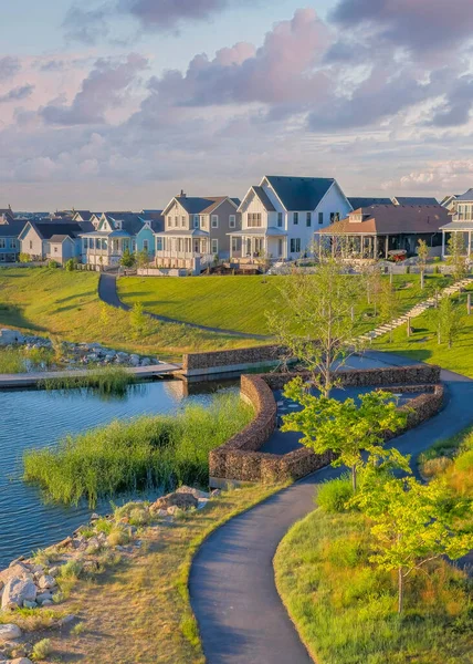 Gün batımında, Daybreak yerleşim yerindeki Oquirrh Gölü 'nde dikey kabarık bulutlar ve yanında beton kaldırımlar. Şafak 'ın yerleşim alanının yüksek açılı görüntüsü otlar ve çalılarla dolu bir tepeden..