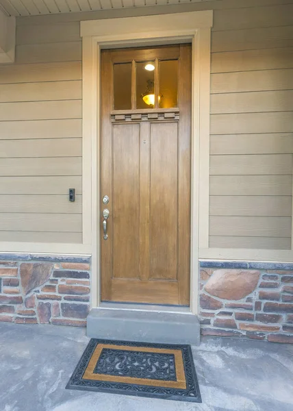 垂直的木制前门与玻璃窗和时髦的门垫 房子的前廊 有栏杆和米黄色乙烯木和石材镶边的外墙 — 图库照片