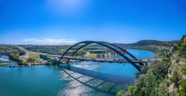 Austin, Texas- Through arch bridge over the Colorado River. Vehicles passing on the large bridge against the view of buildings and clear sky background.