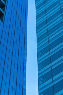 Clear sky in between the two tall buildings with glass walls- Austin, Texas. Part of two skyscrapers exterior with glass walls in a low angle view.