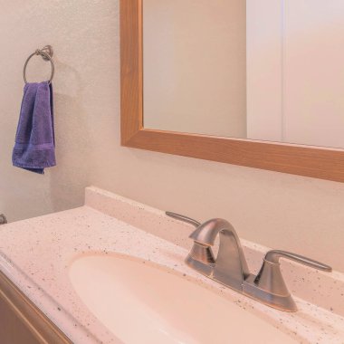 Kare banyo içi gri fayans döşemesi ve granit kaplama ve çerçeveli aynalı gösterişli. Küvetin yanında bir klozet var. Etrafında ahşap desenli fayanslar ve plastik duş perdesi var..