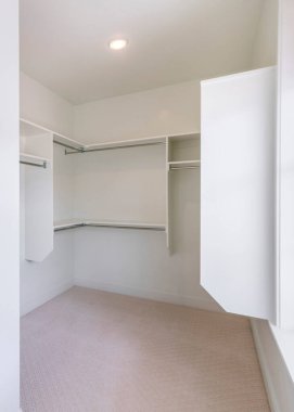 Pencere ve halılı döşemeleri olan bir dolap. Önde bölme rafları var ve arkada metal çubuklar olan raflar monte edilmiş..