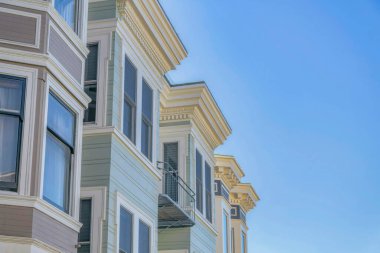 Koyu pencereli evler ve mavi gökyüzüne karşı gri panelli duvarlar. Güneşli bir günde, San Francisco California yerleşim bölgesindeki evlerin dış görünüşü.