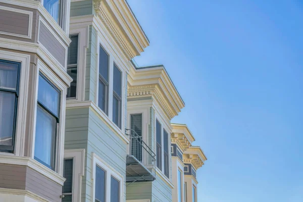 Houses with bay windows and gray panelled walls against blue sky. Exterior view of homes in San Francisco California residential neighborhood on a sunny day.