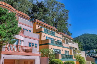 Açık mavi gökyüzü ve ağaçlarla kaplı San Francisco California evleri. Güneşli bir günde mahallede evleri olan bir emlak arazisi..