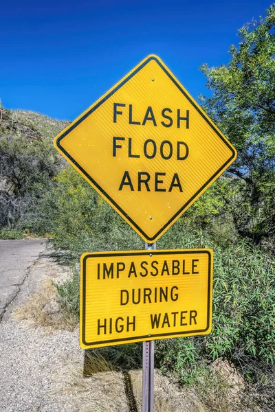 Signage warning at a flash flood area along a hiking trail in Sabino Canyon. Views at the national state park in Arizona recreation area with blue sky on a scenic sunny day.