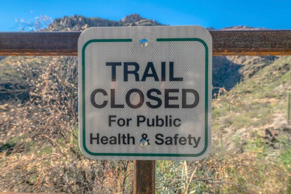 Trail closed sign at the outdoor recreation area in Sabino Canyon Arizona. Close up view of a signage against mountain landscape and blue sky background on a sunny day.