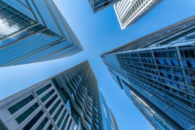 Austin Texas caddesinden modern binalar ve açık mavi gökyüzü. Ofislere ya da apartmanlara bakıyorum. Ön cephesinde cam pencereler var. Güneşi ve gökyüzünü yansıtıyor..