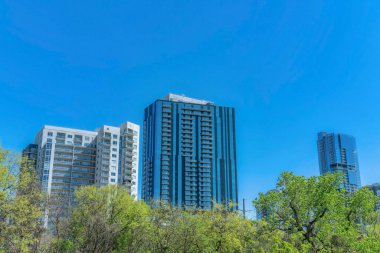 Austin Texas 'ta parlak mavi gökyüzü geçmişi olan bir apartman dairesi. Güneşli bir günde manzaralı şehir silueti modern konut mimarisine sahip konut binalarının yer aldığı.
