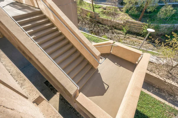 View from above of outdoor stairs going inside a building in Austin Texas. Looking down on a stairway with concrete steps and metal railings on a sunny day.