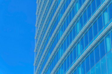 Austin Texas 'taki modern bir ofis binasının dışı açık mavi gökyüzüne karşı. Şehir merkezi, bulutsuz gökyüzünü yansıtan cam bir cephe içeren gökdelen manzaralı..