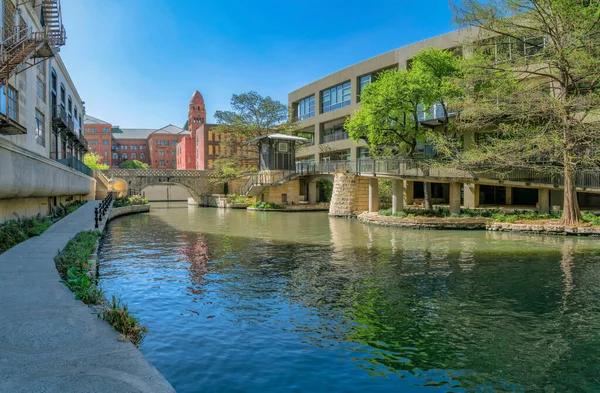 Güneşli bir günde San Antonio Teksas 'taki nehir yürüyüşünün manzarası. Asfalt yollar, köprü ve binalar sakin bir kanala ve mavi gökyüzüne sahiptir..