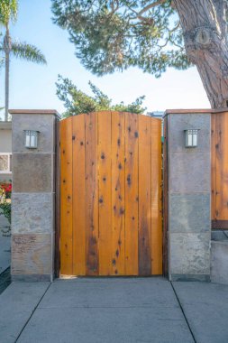 La Jolla, California kiremitli sütunların arasında tek bir tahta kapı girişi var. Arka planda ağaçlar ve gökyüzü manzaralı kapalı bir evin girişinde beton kaldırım..