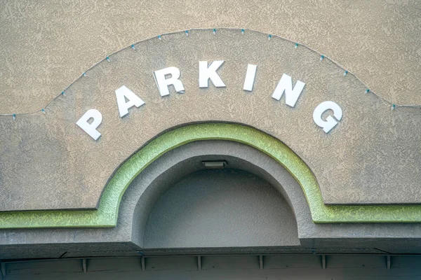 Parking sign on the wall above the arched entrance at downtown Tucson, Arizona. Painted gray concrete wall with parking letters with stringlights above the letters.