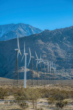 Palm Springs, California yel değirmeni çelik kulesi ve kafes kulelerindeki yel değirmenleri. Dağlara karşı bir çöl arazisindeki rüzgar kanalları..