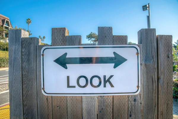 La Jolla, California- Signage with left and right arrow above the Look warning. Signage on a vertical wood planks wall against the sky and road at the back.