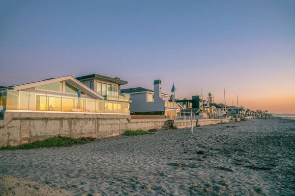 拉乔拉 加利福尼亚州 日落时 海滨沙滩上的一排海滨房屋 在房子的右边 有一个沙滩海岸 有反光玻璃栅栏和窗户 — 图库照片