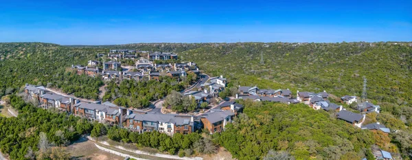 Panorama in an aerial view of an apartment complex buildings in Austin, Texas. Multi-storey apartment complex buildings in the middle of green trees and a view of clear blue sky.