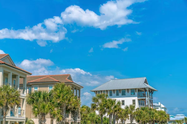 Destin, Florida- Palm trees at the front of beach houses. Front exterior of houses with balconies against the blue sky background.