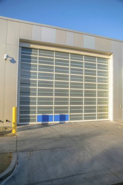 Güvenlik kamerası ve cam garaj kapısı olan modern bir garaj. Phoenix, Arizona. Mavi gökyüzüne karşı cam panelleri olan uzun bir garaj kapısı..
