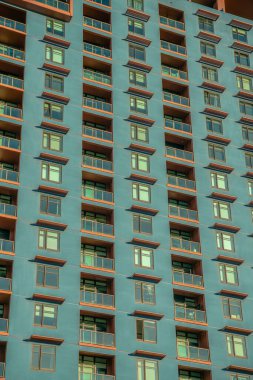 Balkonlu ve mavi yeşil duvarlı apartman cephesi Phoenix, Arizona. Çok katlı, dış tarafı cam parmaklıklarla kaplı, pencerelere yakın, güneşlikli bir bina..