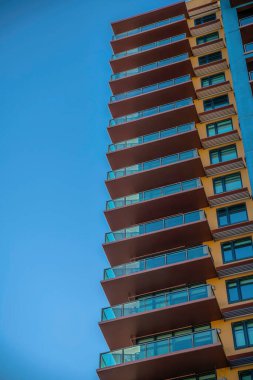 Camdan balkon korkulukları olan çok katlı bir bina. Phoenix, Arizona. Pencerelerin yanında tenteli balkonları olan yüksek bir binanın alçak açılı görüntüsü..