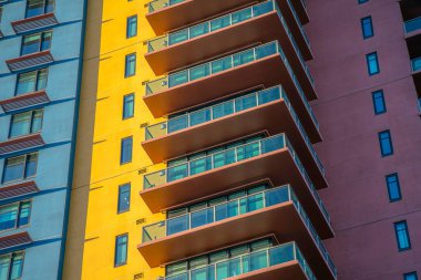 Phoenix, Arizona- Sarı, mavi ve kırmızı duvarlı bir bina. Pencere güneşlikleri ve cam parmaklıklı balkonları olan bir binanın alçak açılı görüntüsü.