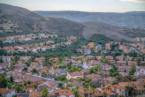 View from a hiking trail of villas on a subdivision at San Clemente, California. Mountainside suburban residential area with a view of mountain range and sky.