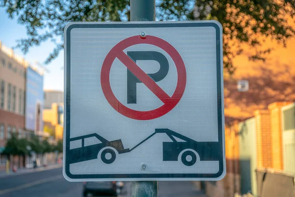 No parking and tow away sign on a post- Phoenix, Arizona. Close-up of a road sign against the blurred background view of the street.