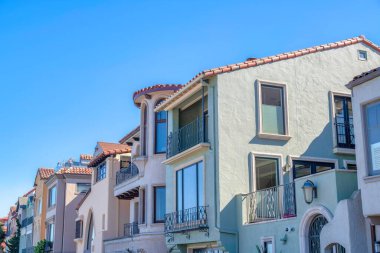 San Francisco, CA 'da bir dizi boyalı Akdeniz evi. Korkuluklu evlerin ve yansıtıcı cam camlı pencerelerin dış yüzeyi..