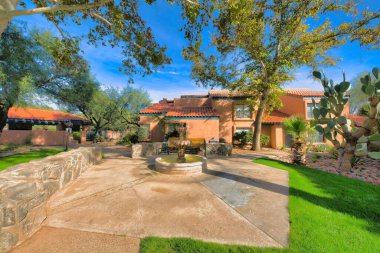 Tucson, Arizona 'daki evlerin yanında küçük bir çeşme ve bahçe tezgahı. Solda ve ortada evlerin karşısında taş bir duvar ve sağda uzun bir kaktüs manzarası var..