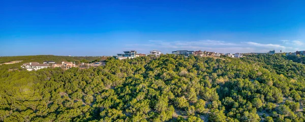 Austin, Texas- Rich residential area on top of a hill in panoramic view. Large residential buildings on top of a hill with trees on the slope against the clear blue sky background.