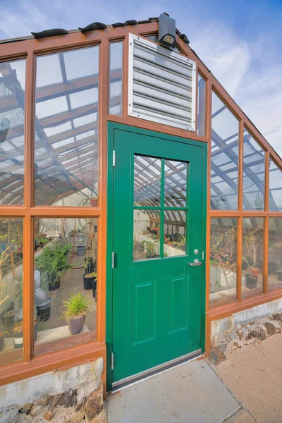 亚利桑那州图森的温室外部 不锈钢通风下方有绿色的门 带有玻璃面板的温室 可看到里面的盆栽植物 — 图库照片