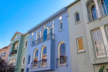 San Francisco, CA 'da dekoratif sütunları ve kemerli pencereleri olan bitişik italik evler. Pencere parmaklıkları ve balkonları alçak açılı üç katlı evler..