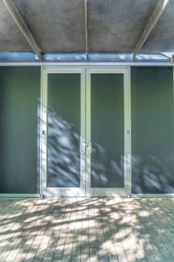 Austin Texas 'taki bir ticari binanın çelik çerçeveli çift kapılı kapısı. Girişi gören bir binanın dışı. Güneş ışığı zemine gölge düşürüyor..