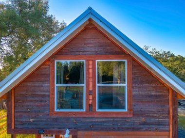 Navarre Florida 'da çatısı mavi gökyüzüne karşı olan bir evin üst katında. Eski evin kahverengi ahşap dış duvarı ve cam pencereleri manzaralı arka bahçeyi yansıtıyor..