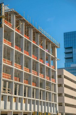 Austin Texas 'ta inşaat halindeki bitmemiş bir binanın dış görünüşü. Binanın içinde bir otopark ve modern cam gökdelen de mavi gökyüzüne karşı görülebilir..